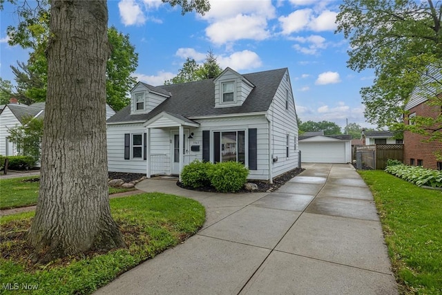 5963 Porter Rd, North Olmsted, OH 44070 - cape cod house featuring a garage, roof with shingles, and an outdoor structure