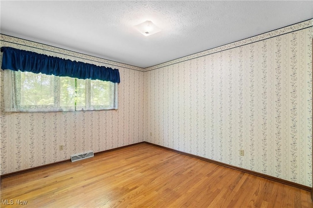4512 Conestoga Trl, Copley, OH 44321 - unfurnished room featuring light wood finished floors, wallpapered walls, baseboards, and a textured ceiling