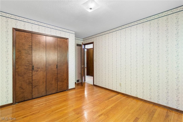 4512 Conestoga Trl, Copley, OH 44321 - unfurnished bedroom featuring light wood finished floors, wallpapered walls, a closet, and baseboards