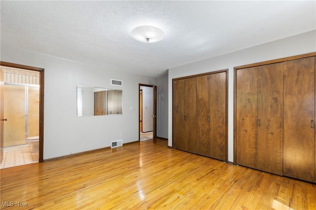 4512 Conestoga Trl, Copley, OH 44321 - unfurnished bedroom featuring light wood-style floors, multiple closets, ensuite bathroom, a textured ceiling, and baseboards