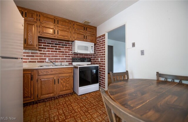 142 Marion Ave, Mogadore, OH 44260 - kitchen with white appliances, a sink, dark floors, light countertops, and brown cabinetry