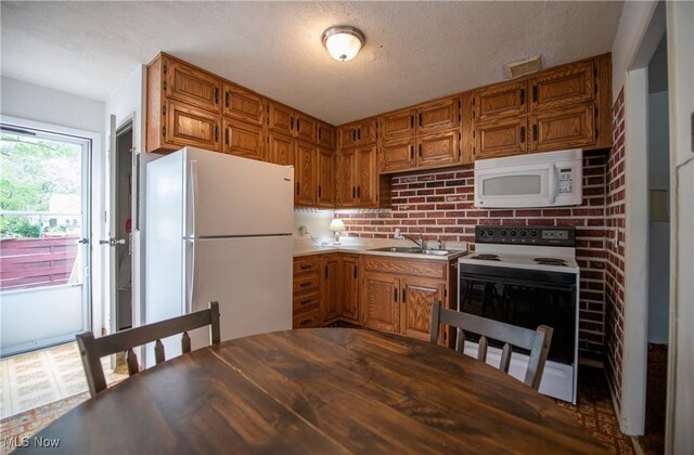 142 Marion Ave, Mogadore, OH 44260 - kitchen with white appliances, a sink, brown cabinetry, and a textured ceiling