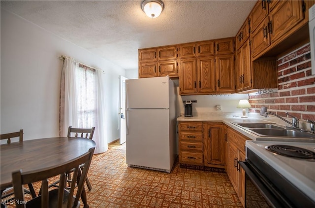 142 Marion Ave, Mogadore, OH 44260 - kitchen featuring freestanding refrigerator, a sink, range with electric stovetop, a textured ceiling, and brown cabinets