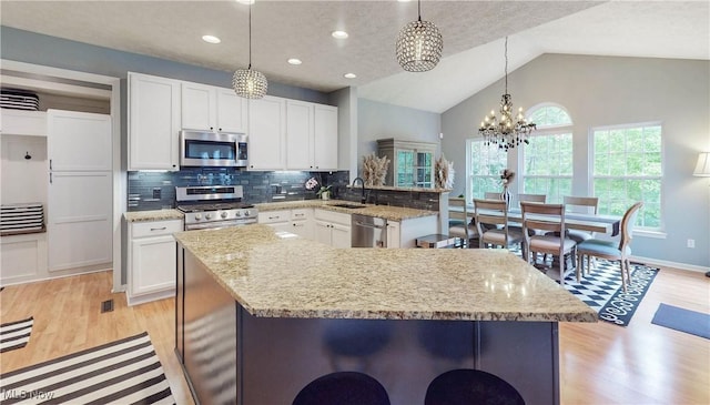 218 Treetop Spur, Copley, OH 44321 - kitchen featuring stainless steel appliances, a chandelier, backsplash, light wood-style flooring, and white cabinetry