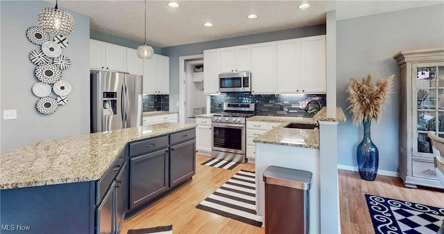218 Treetop Spur, Copley, OH 44321 - kitchen with appliances with stainless steel finishes, light wood-style flooring, white cabinetry, decorative backsplash, and recessed lighting