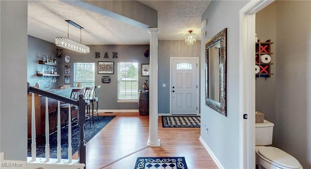218 Treetop Spur, Copley, OH 44321 - entryway with decorative columns, wood finished floors, baseboards, a textured ceiling, and bar