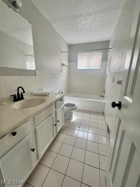 23855 Banbury Cir, Warrensville Heights, OH 44128 - full bath featuring toilet, vanity, a textured ceiling, bathtub / shower combination, and tile walls