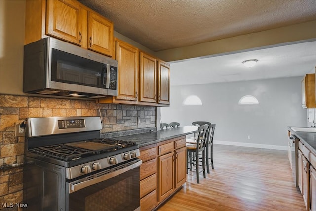 4604 7th Ave, Vienna, WV 26105 - kitchen with appliances with stainless steel finishes, light wood-type flooring, dark countertops, baseboards, and a textured ceiling