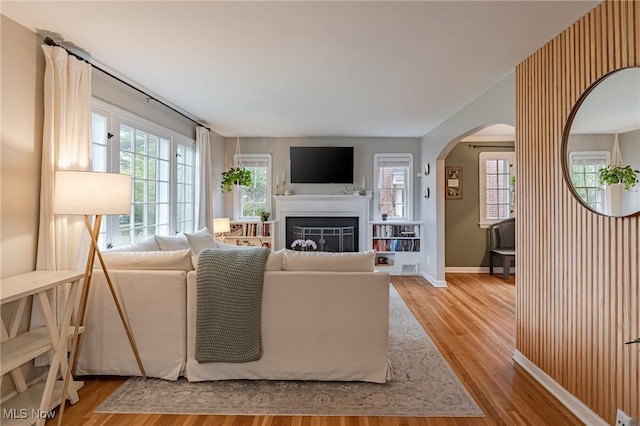 4206 Bushnell Rd, University Heights, OH 44118 - living room featuring arched walkways, wood finished floors, a glass covered fireplace, and baseboards