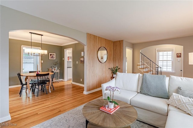 4206 Bushnell Rd, University Heights, OH 44118 - living area with arched walkways, light wood-style flooring, baseboards, stairs, and a chandelier