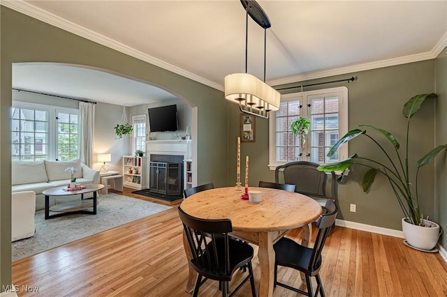 4206 Bushnell Rd, University Heights, OH 44118 - dining area featuring wood finished floors, a fireplace with raised hearth, ornamental molding, arched walkways, and baseboards