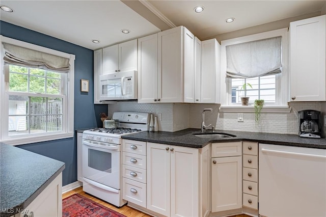 4206 Bushnell Rd, University Heights, OH 44118 - kitchen with white appliances, a sink, white cabinets, light wood finished floors, and tasteful backsplash