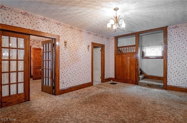 52 20th St SW, Barberton, OH 44203 - unfurnished room with wallpapered walls, a chandelier, carpet floors, a textured ceiling, and french doors