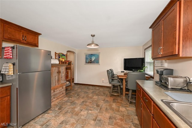 123 Wabash Ave, Orrville, OH 44667 - kitchen featuring freestanding refrigerator, arched walkways, dark stone finish floors, a sink, and baseboards