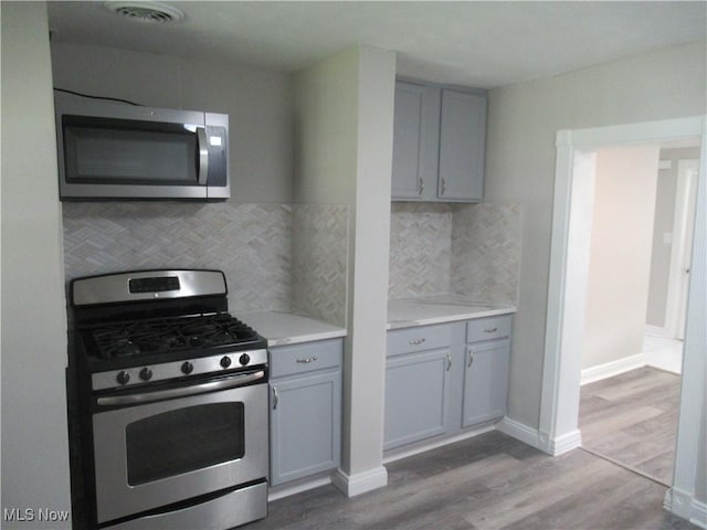 6453 Poplar Dr, Independence, OH 44131 - kitchen with stainless steel appliances, gray cabinets, light wood-style flooring, backsplash, and baseboards