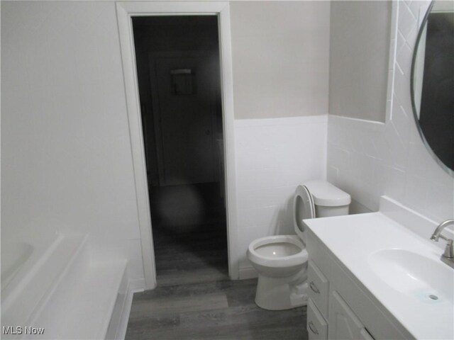 6453 Poplar Dr, Independence, OH 44131 - bathroom with wood finished floors, toilet, a bath, vanity, and tile walls