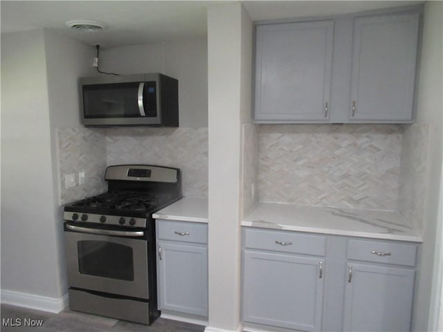 6453 Poplar Dr, Independence, OH 44131 - kitchen featuring appliances with stainless steel finishes, gray cabinets, tasteful backsplash, and light countertops