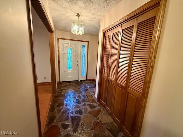 305 Flintwood Dr, Marietta, OH 45750 - foyer entrance featuring a chandelier, a textured ceiling, baseboards, and stone floors