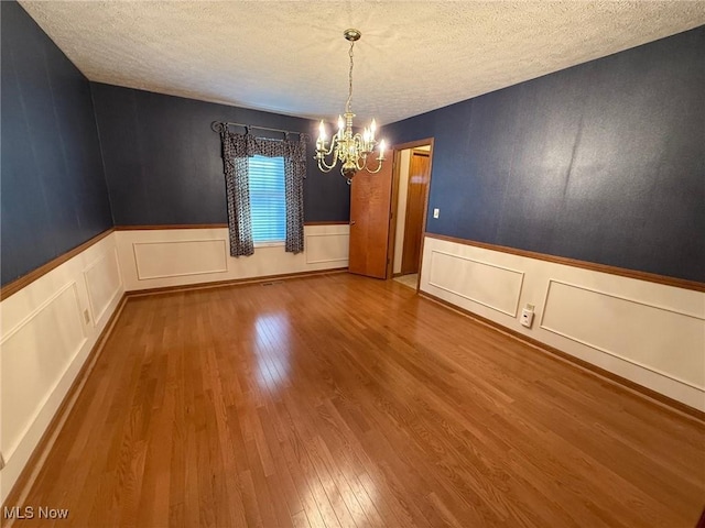 305 Flintwood Dr, Marietta, OH 45750 - unfurnished dining area featuring a chandelier, a textured ceiling, wood finished floors, a wainscoted wall, and a decorative wall