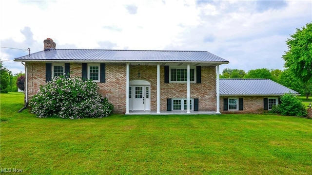23595 Sandy Creek Rd, Minerva, OH 44657 - raised ranch featuring a front lawn, metal roof, a chimney, and brick siding