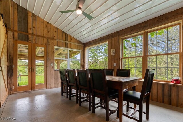15216 Grove Rd SE, Port Washington, OH 43837 - dining space with vaulted ceiling, wood walls, french doors, ceiling fan, and concrete flooring