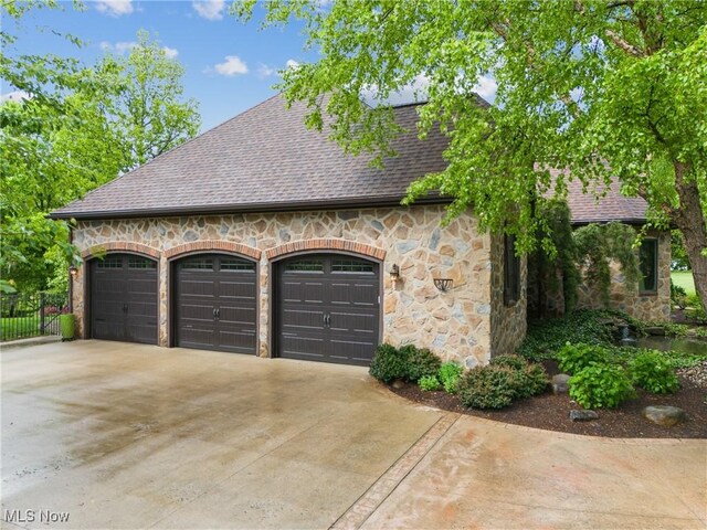 3109 Kennesaw Cir NW, Canton, OH 44708 - view of property exterior with stone siding, roof with shingles, an attached garage, and concrete driveway