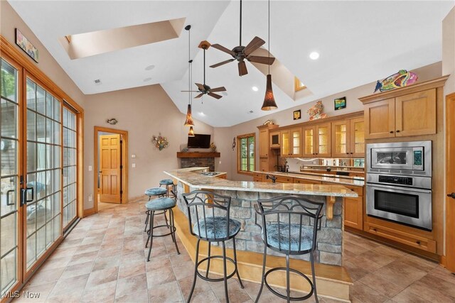 3109 Kennesaw Cir NW, Canton, OH 44708 - kitchen featuring appliances with stainless steel finishes, a kitchen bar, a skylight, a large island, and glass insert cabinets