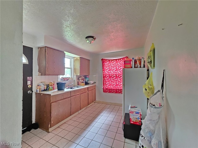 72 Idaho Rd, Austintown, OH 44515 - kitchen featuring a textured ceiling, light countertops, freestanding refrigerator, light tile patterned flooring, and brown cabinetry