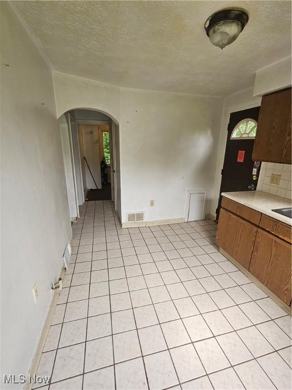 72 Idaho Rd, Austintown, OH 44515 - unfurnished dining area featuring arched walkways, a textured ceiling, and light tile patterned floors
