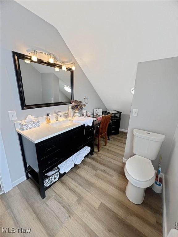 9007 Plymouth Ave, Garfield Heights, OH 44125 - bathroom with vaulted ceiling, wood finished floors, toilet, vanity, and baseboards
