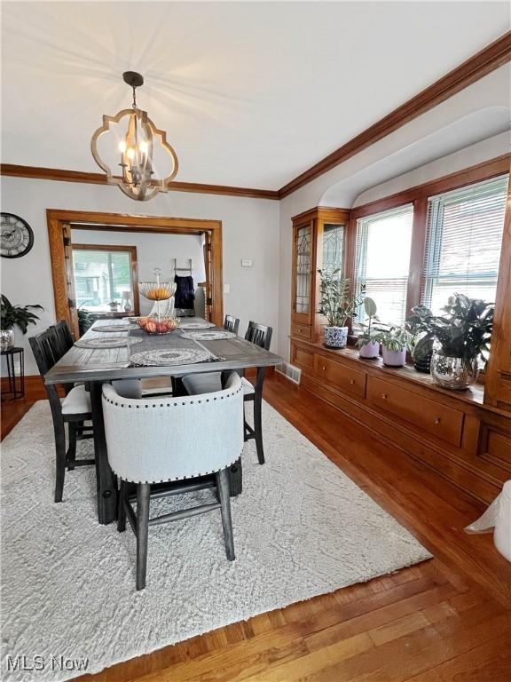 9007 Plymouth Ave, Garfield Heights, OH 44125 - dining room with a chandelier, plenty of natural light, wood finished floors, and crown molding