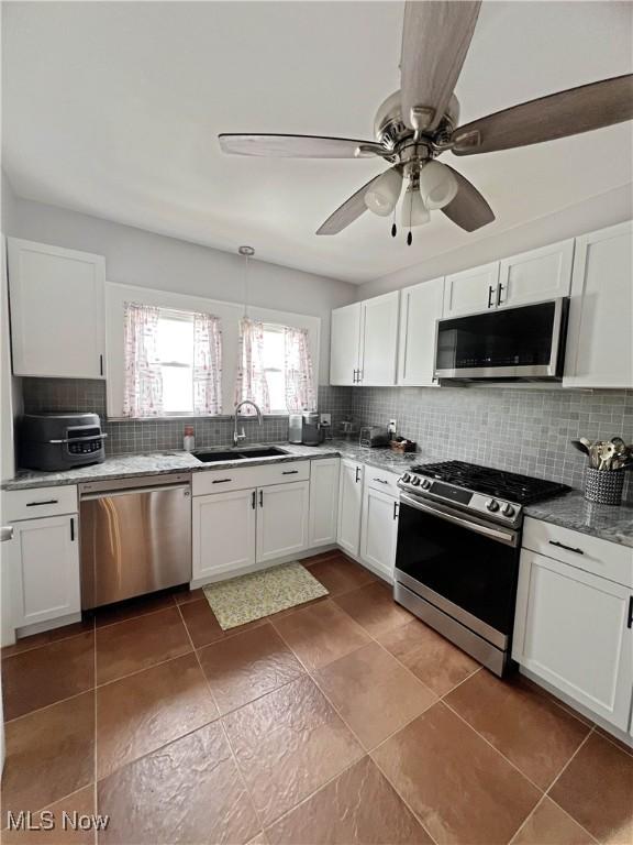 9007 Plymouth Ave, Garfield Heights, OH 44125 - kitchen featuring stainless steel appliances, a sink, backsplash, white cabinets, and ceiling fan