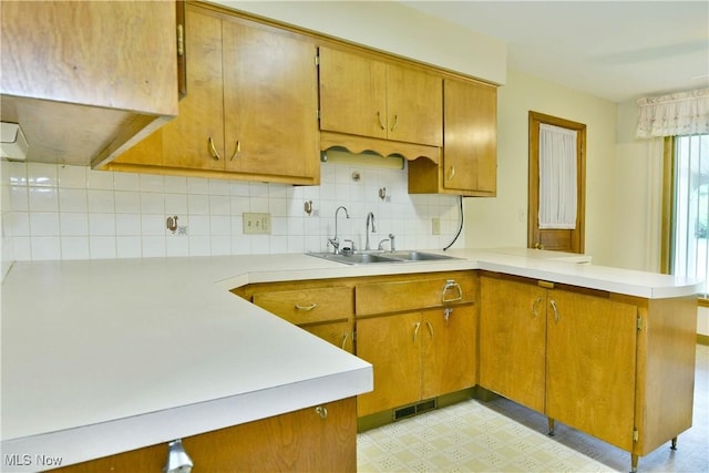 3763 E River Rd, Newton Falls, OH 44444 - kitchen with a sink, a peninsula, light countertops, decorative backsplash, and brown cabinetry