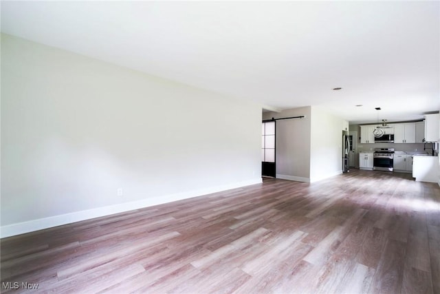 351 Cranberry Run, Boardman, OH 44512 - unfurnished living room with a barn door, wood finished floors, baseboards, and a sink