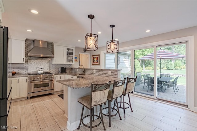 30699 Gates Mills Blvd, Pepper Pike, OH 44124 - kitchen with high end stainless steel range, wall chimney range hood, a sink, white cabinetry, and a peninsula