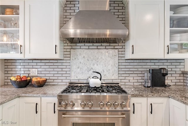30699 Gates Mills Blvd, Pepper Pike, OH 44124 - kitchen featuring wall chimney exhaust hood, high end stove, decorative backsplash, and white cabinetry