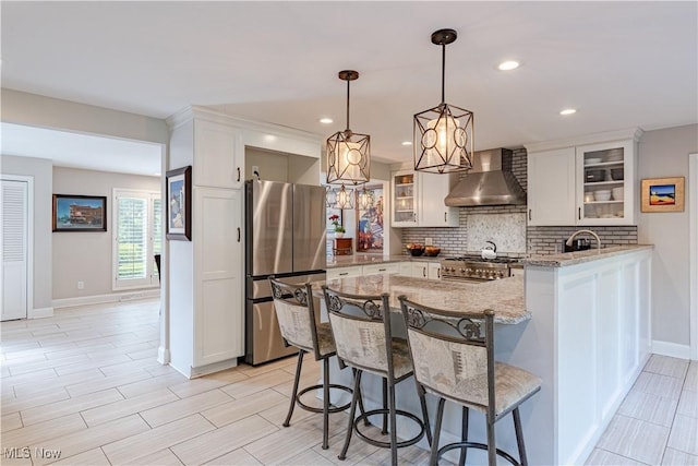 30699 Gates Mills Blvd, Pepper Pike, OH 44124 - kitchen with wall chimney exhaust hood, appliances with stainless steel finishes, decorative backsplash, light stone counters, and baseboards