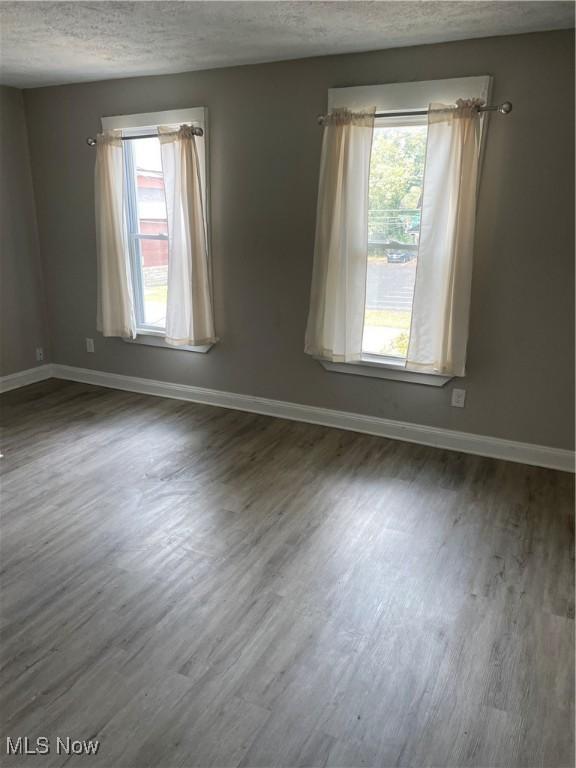 1717 Clark Ave, Cleveland, OH 44109 - spare room featuring a textured ceiling, healthy amount of natural light, wood finished floors, and baseboards