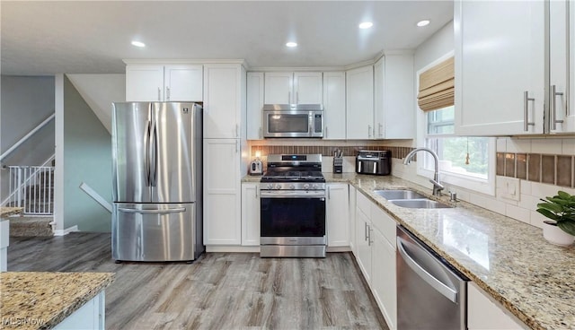 1379 S Polen Ave, Mogadore, OH 44260 - kitchen with appliances with stainless steel finishes, a sink, light wood-style flooring, white cabinets, and tasteful backsplash