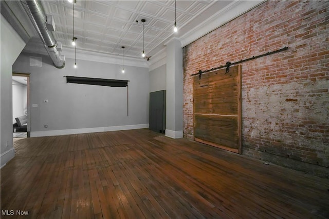 38 E Main St, Shelby, OH 44875 - spare room featuring hardwood / wood-style flooring, brick wall, baseboards, and a barn door