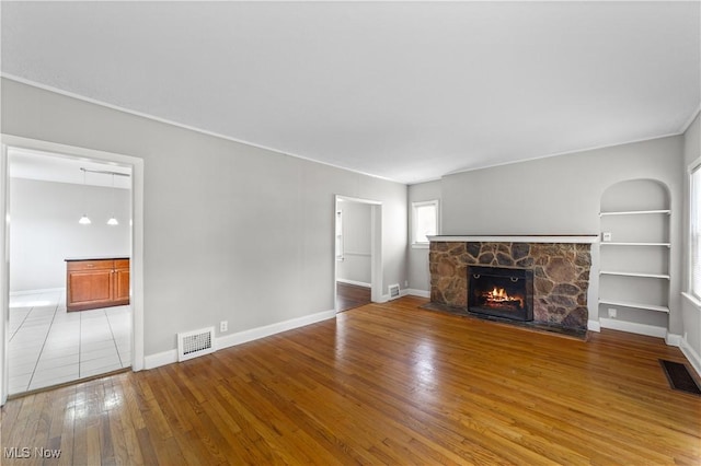 5688 Shawnee Dr, Lyndhurst, OH 44124 - unfurnished living room with a stone fireplace, hardwood / wood-style flooring, built in shelves, and baseboards