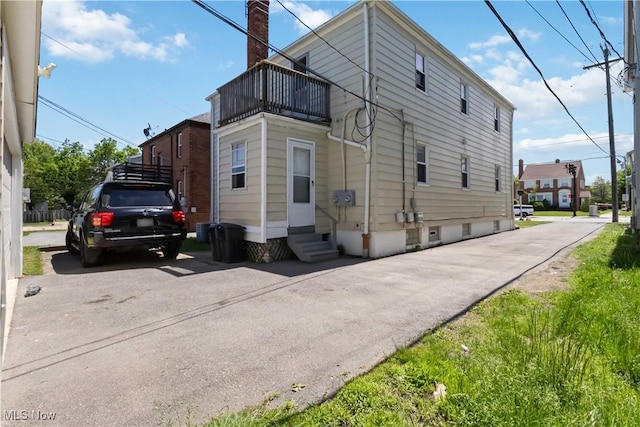 13641 Cedar Rd, University Heights, OH 44118 - back of house with a balcony, entry steps, a chimney, and driveway