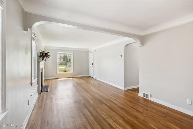 13641 Cedar Rd, University Heights, OH 44118 - unfurnished living room featuring arched walkways, wood finished floors, baseboards, a fireplace, and crown molding