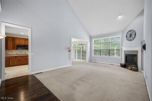 4819 Trails End Ct, Westlake, OH 44145 - unfurnished living room featuring high vaulted ceiling, a fireplace, baseboards, light wood-type flooring, and light colored carpet