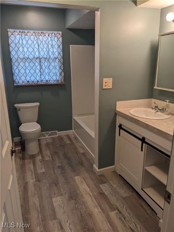 871 Chinook Ave, Akron, OH 44305 - bathroom featuring vanity, toilet, wood finished floors, a bathtub, and baseboards