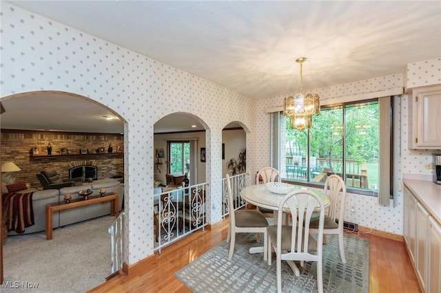 5761 Goodman Cir, North Royalton, OH 44133 - dining room featuring wallpapered walls, a chandelier, arched walkways, light wood finished floors, and baseboards