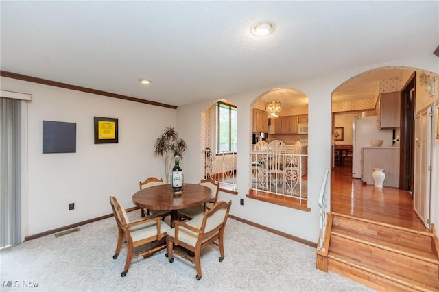5761 Goodman Cir, North Royalton, OH 44133 - dining room with arched walkways, baseboards, a chandelier, light carpet, and ornamental molding