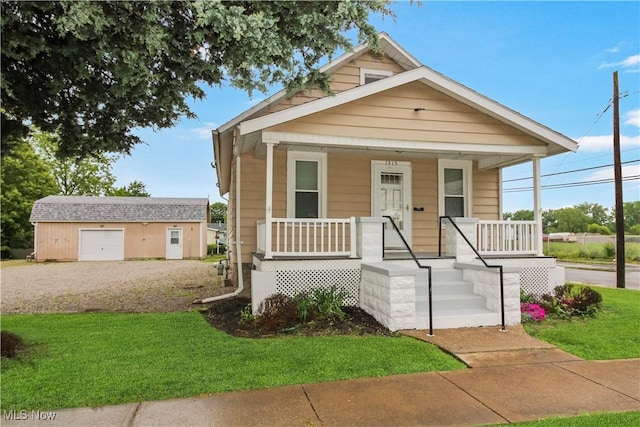 1515 E 3rd St, Port Clinton, OH 43452 - shotgun-style home with covered porch, an outbuilding, a front yard, and a detached garage