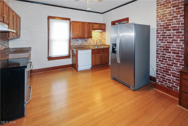 1515 E 3rd St, Port Clinton, OH 43452 - kitchen with appliances with stainless steel finishes, brown cabinets, light wood-type flooring, backsplash, and under cabinet range hood