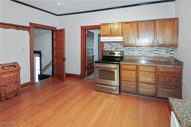 1515 E 3rd St, Port Clinton, OH 43452 - kitchen with stainless steel electric range, under cabinet range hood, light wood-style flooring, tasteful backsplash, and ornamental molding